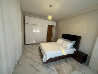 a bedroom with a bed with marble floors at Licht & ruim 2-slaapkamer appartement met airco & Wifi - rustig wijk Marrakesh in Marrakech