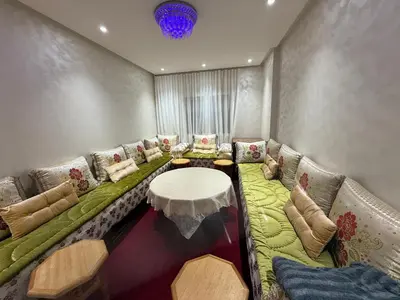 a living room with a long couch with a table at Licht & ruim 2-slaapkamer appartement met airco & Wifi - rustig wijk Marrakesh in Marrakech