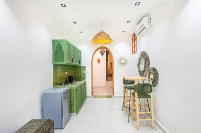 a kitchen with green cabinets and a table with stools at Casa Coloré terrace and bohemian charm in Marrakech