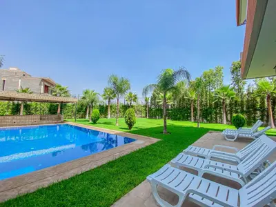 a backyard with a swimming pool and lawn with lounge chairs at Argan golf in Marrakech