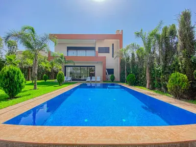 a villa with a swimming pool in front of a house at Argan golf in Marrakech