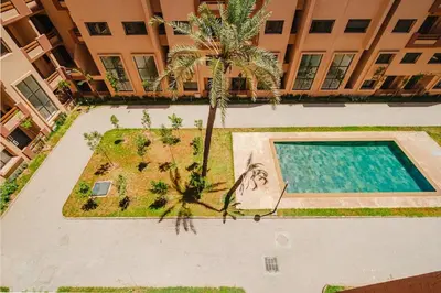 an aerial view of a building with a swimming pool and a palm tree at Modern Studio with Pool in Marrakech