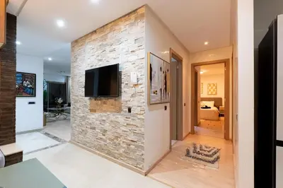 a living room with a stone wall with a flat screen tv at Luxury apartment in Prestigia Opale in Marrakech