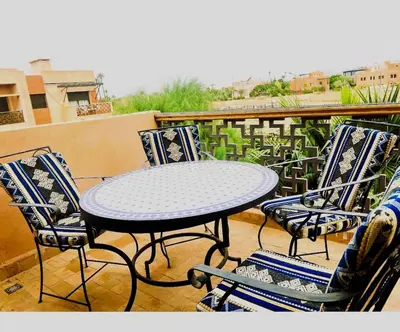 a table and four chairs on a balcony at Palmeraie, Appart chic Suite & Accès à 3 Piscines in Dar Caïd Layadi