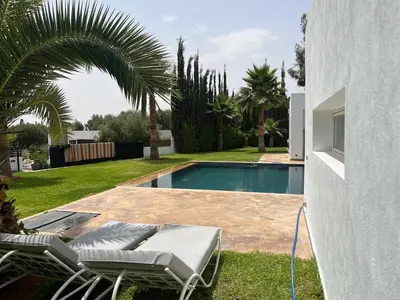 a swimming pool with two lounge chairs next to a house at Villa Zaara in Sehib Foukani