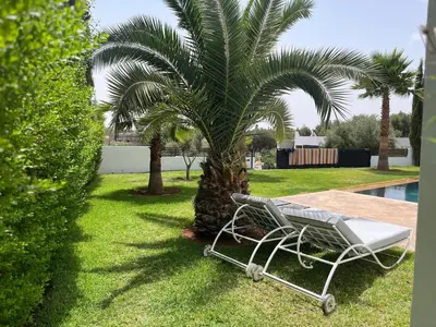 a palm tree and a chair next to a pool at Villa Zaara in Sehib Foukani