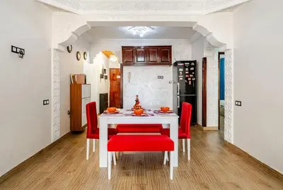a dining room with a white table and red chairs at Princess in Marrakech