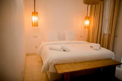 a bedroom with a white bed and a wooden table at Riad A l'Ombre du Palais in Marrakech