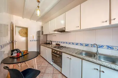 a kitchen with white cabinets and a sink and a table at Luxury 2BR Apt in Gueliz, Pools, Parking,Elevator in Marrakech