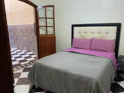 a bedroom with a bed with purple pillows on it at Garden View Comfort Apartment in Marrakech