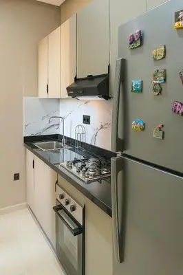 a kitchen with a stove and a refrigerator at Appartement Confort & Sérénité Mabroka Marrakech in Marrakech