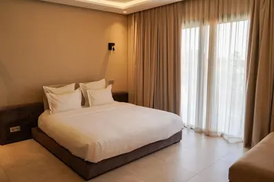 a bedroom with a bed with white sheets and a window at Villa NAHA in Marrakech