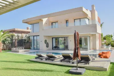 a villa with a pool and lawn with umbrellas at Villa NAHA in Marrakech