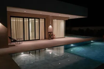 a house with a swimming pool at night at Villa NAHA in Marrakech
