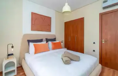 a bedroom with a white bed with orange and blue pillows at Appartement luxe avec vue imprenable sur le golf in Marrakech
