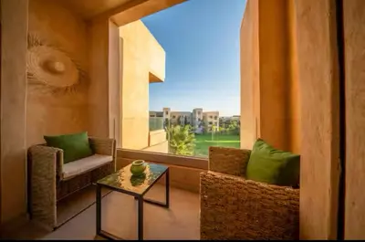a room with two chairs and a table and a window at Appartement luxe avec vue imprenable sur le golf in Marrakech