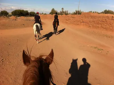 two people riding horses down a dirt road at La Vie En Rose - Horses & Dogs House in Marrakech