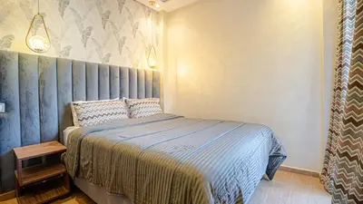 a bedroom with a bed with a blue comforter at Bel appart vue piscine dans résidence sécurisée in Marrakech