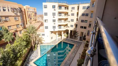 an apartment with a swimming pool in front of a building at Bel appart vue piscine dans résidence sécurisée in Marrakech