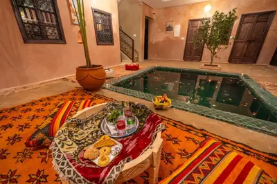 a table with a plate of food on it in front of a pool at Riad Lalla Fatima Marrakech in Marrakech