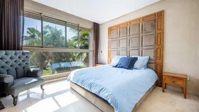 a bedroom with a bed and a chair and a window at Villa de luxe in Marrakech