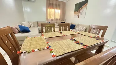 a dining room table with four chairs and a couch at Private Apartment Near Marrakech Airport in Marrakech