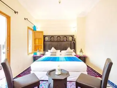 a bedroom with a large bed and two chairs at Arabian Riad Marrakech in Marrakech