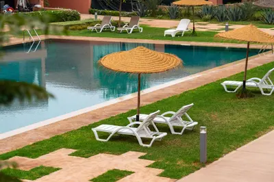 a group of chairs and umbrellas next to a swimming pool at AyaMi Marrakech Luxury Stay in Marrakech
