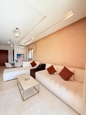 a living room with two white couches and a table at Appartement Confortable Vus Sur Piscine A Prestigia in Marrakech