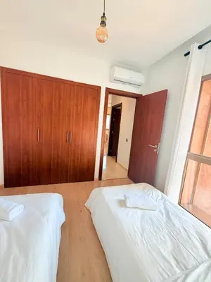 a bedroom with two beds and wooden cabinets at Appartement Confortable Vus Sur Piscine A Prestigia in Marrakech