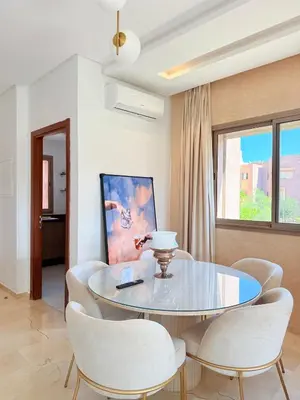 a dining room with a glass table and white chairs at Appartement Confortable Vus Sur Piscine A Prestigia in Marrakech