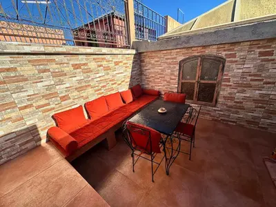 a patio with a red couch and a table and chairs at Riyad Ambre in Marrakech