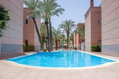 a large blue swimming pool in a building with palm trees at Riyad Ambre in Marrakech