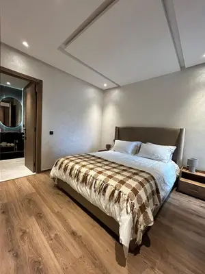 a bedroom with a large bed and a wooden floor at Appartement Moderne - Accès Piscines et Fitness in Marrakech