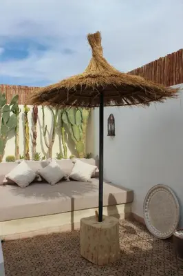 a bed with a large straw umbrella in a room at Riad de charme privatisé au cœur de la médina in Marrakech