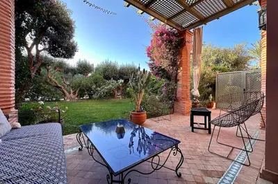a patio with a glass table and chairs on a patio at Garden Aparment in Palmeraie 2 in Marrakech