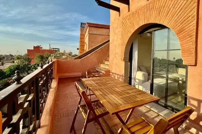 a wooden table and chairs on a balcony at Atlas Golf Resort with Terrace and Pools in Marrakech