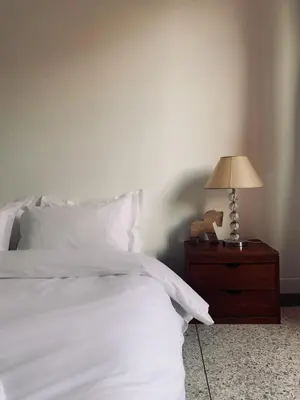 a bed with white sheets and a lamp on a nightstand at Designer apartment with south-facing terrace in Marrakech