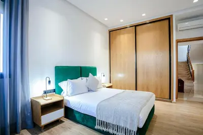 a bedroom with a large bed and a wooden cabinet at Villa Nerolia - Marrakech in Marrakech