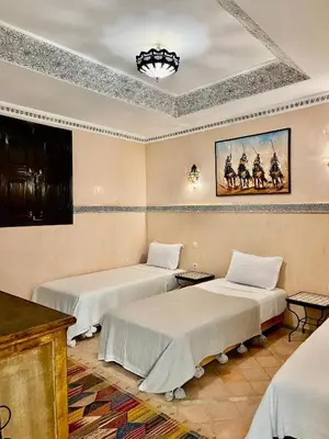 a room with two beds and a painting on the wall at Riad alwafa B&B in Marrakech