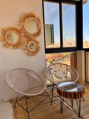 two chairs and a table and mirrors on a wall at Dar Kamyssa Le désert au cœur de Guéliz in Marrakech