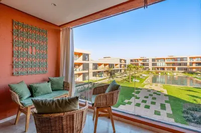 a balcony with a couch and chairs and a large window at Beautiful Apartment with Pool View Noria Golf in Marrakech