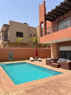 a swimming pool in front of a house at La Villa Ocre in Marrakech