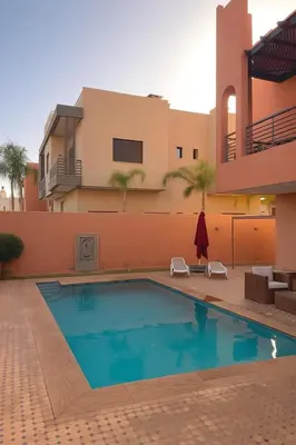 a swimming pool in front of a house at La Villa Ocre in Marrakech