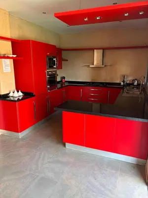 a kitchen with red cabinets and black counter tops at La Villa Ocre in Marrakech