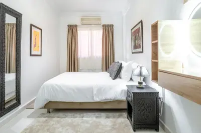 a white bedroom with a bed and a mirror at Appartement de charme à Gueliz - Centre Marrakech in Marrakech