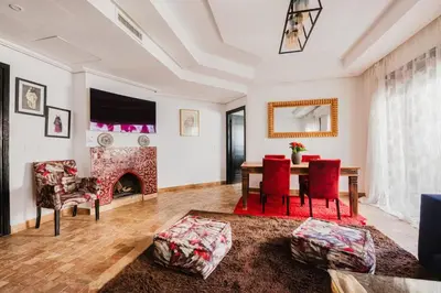a living room with a table and chairs and a fireplace at Cocon au calme Residence Piscine Marrakech in Marrakech