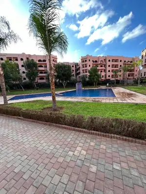 a palm tree in a park with buildings in the background at Cocon au calme Residence Piscine Marrakech in Marrakech
