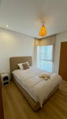 a bedroom with a large white bed with a window at Magnifique appartement in Marrakech