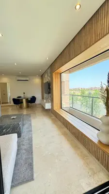 a living room with a large window and a table at Magnifique appartement in Marrakech